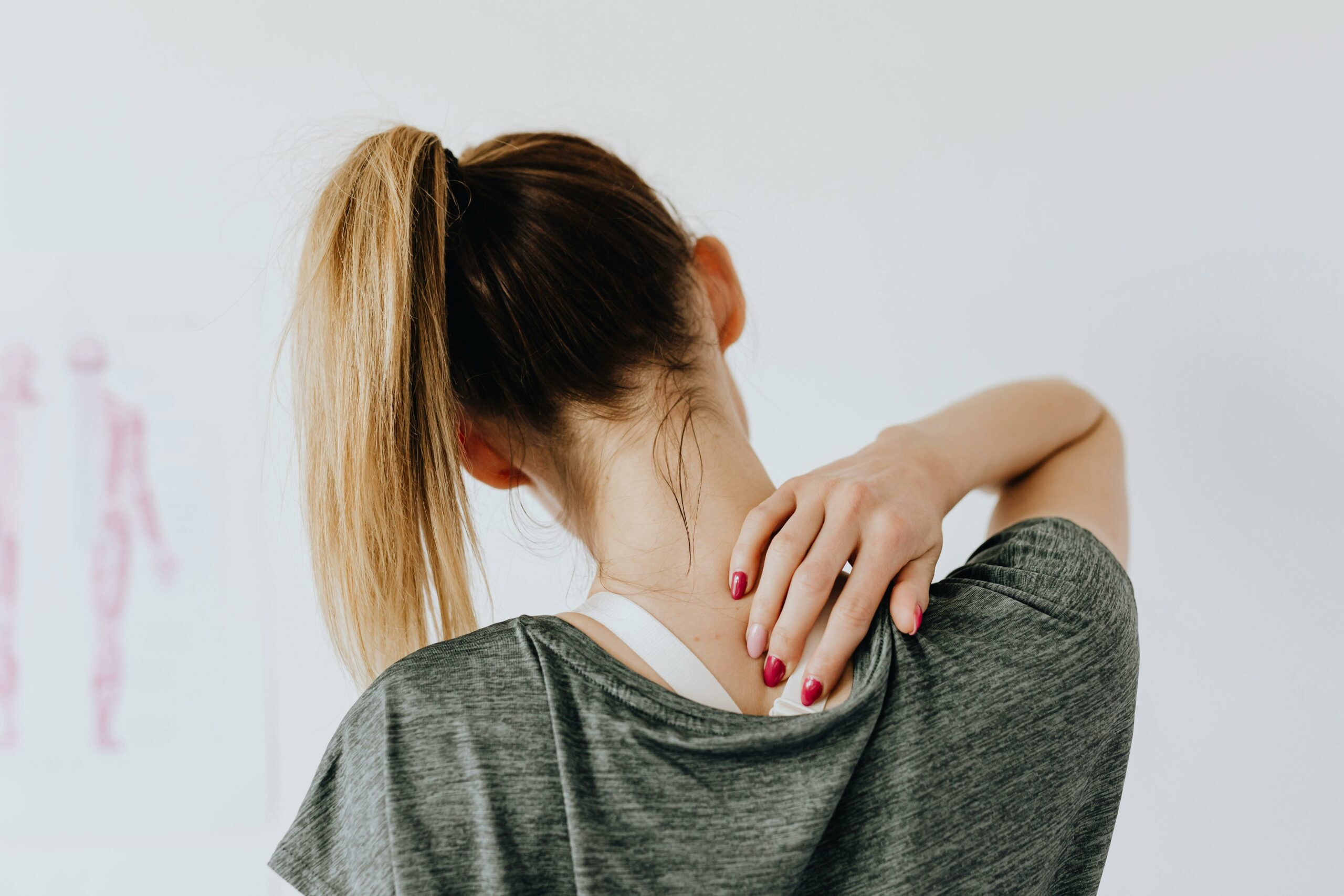 Image d'une femme assise de dos qui se touche la nuque