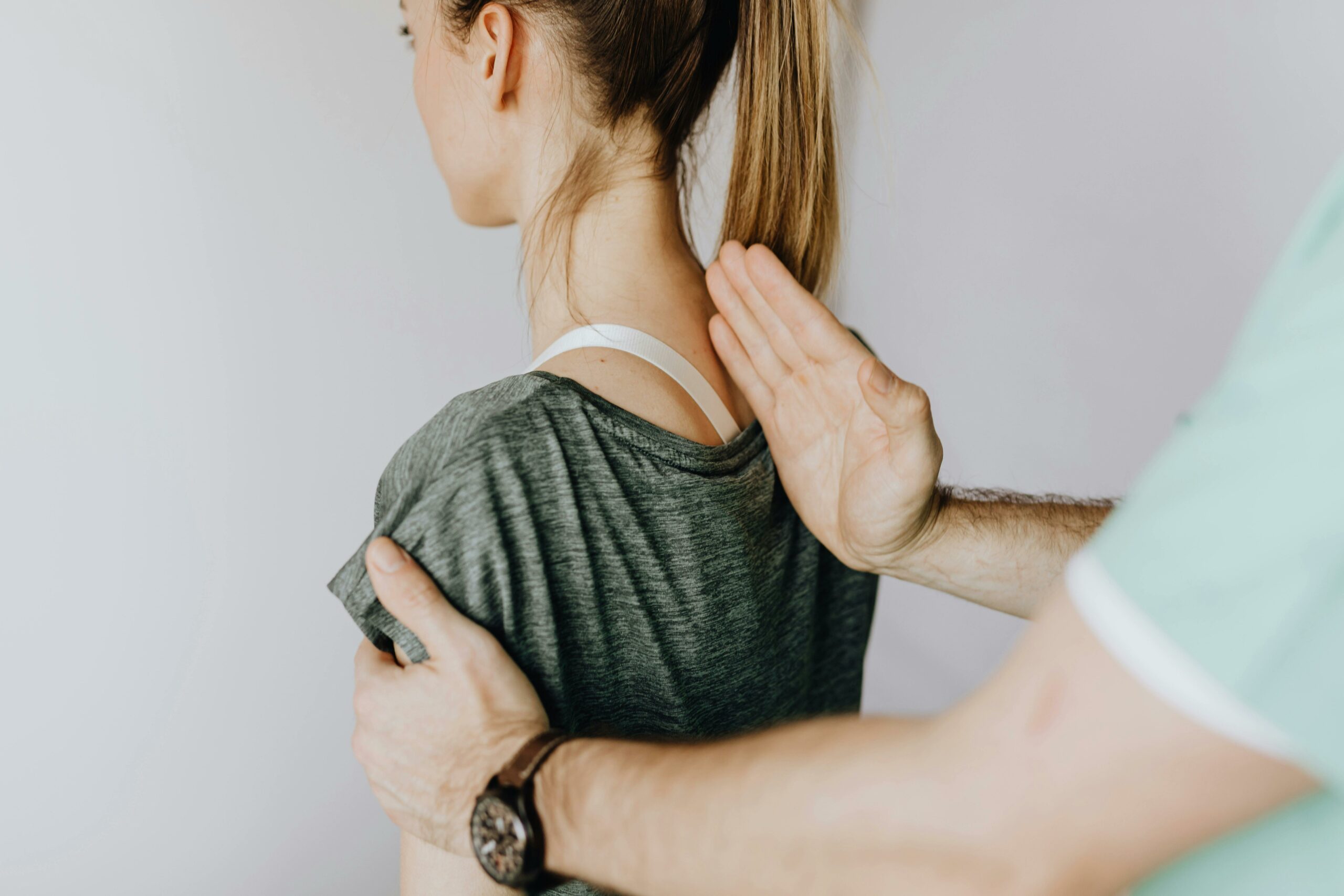 Image d'une femme assise de dos se faisant manipuler par un ostéopathe.