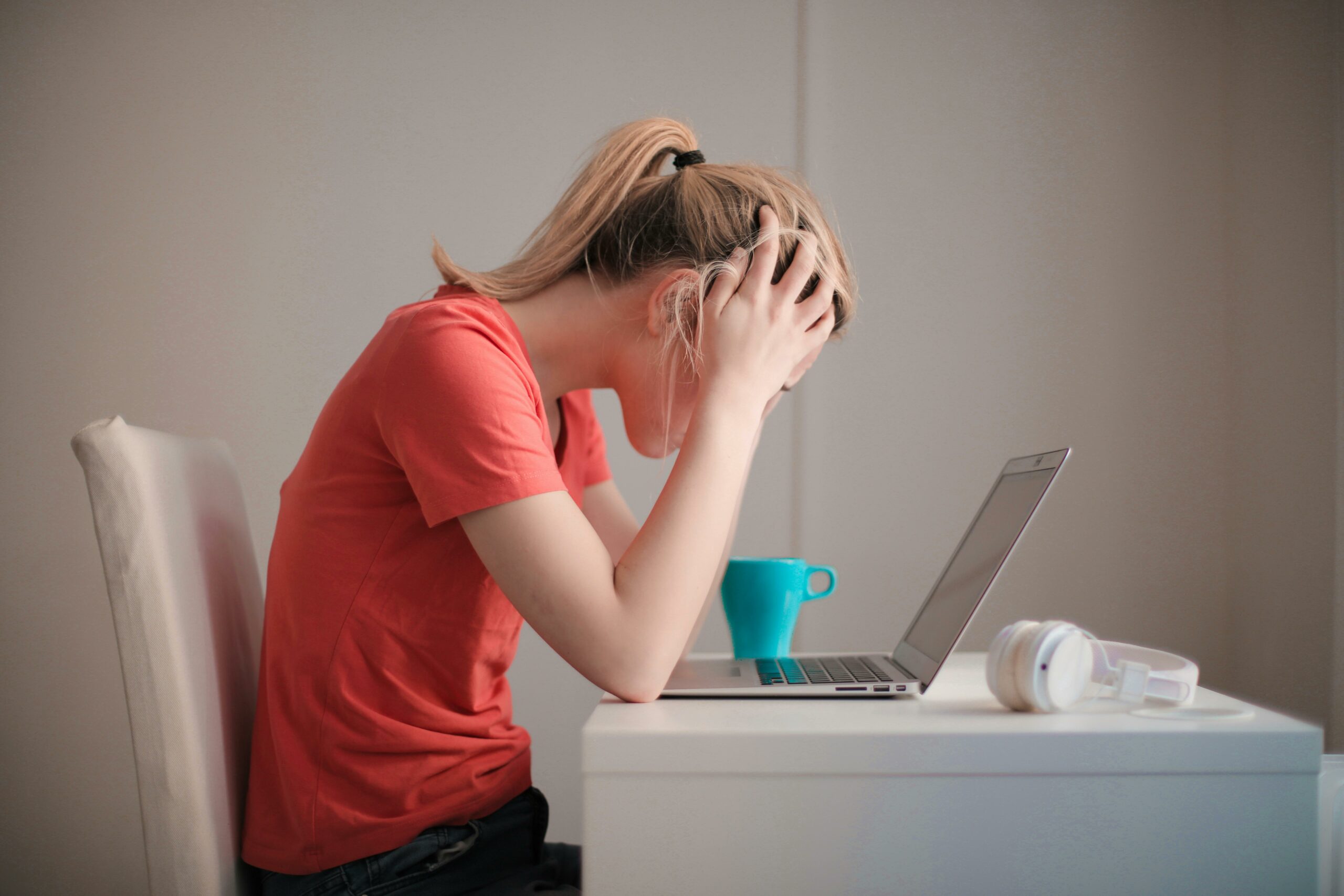 Image d'une femme se tenant la tête face à son ordinateur.