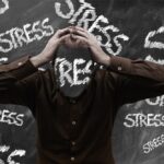 Illustration représenant un homme qui croule sous plusieurs mots "stress"