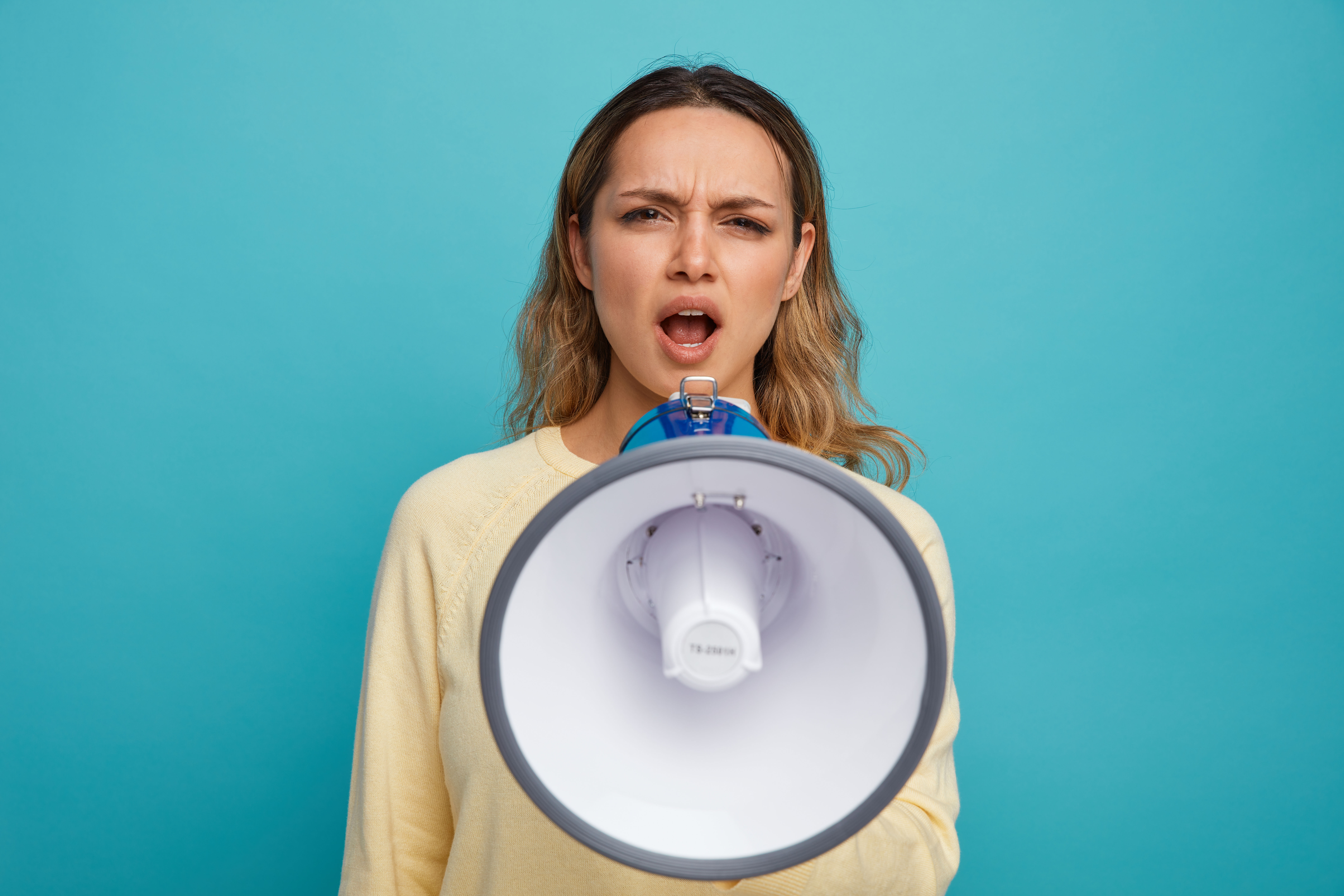 Jeune femme en colère criant dans un mégaphone, représentant l’expression et la libération des émotions en ostéopathie émotionnelle
